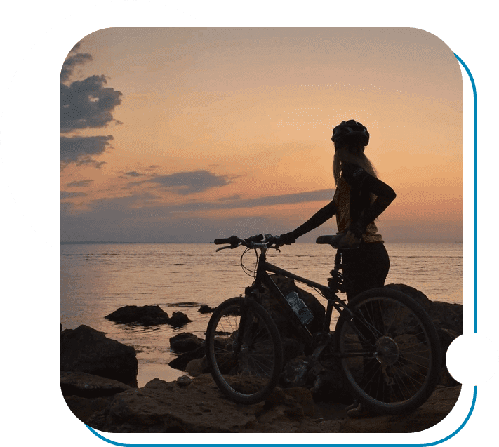 A person standing next to a bike on the beach